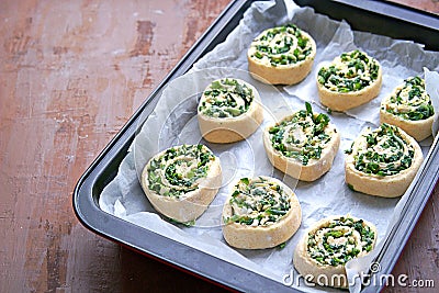 Cooking homemade buns with green onions, nettles, cheese and egg, the third step. Finished shaped buns in the pan for baking. Stock Photo