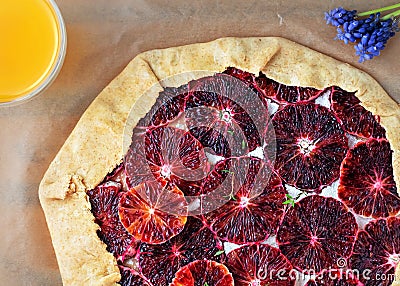 Cooking homemade galette with bloody orange, sugar and thyme. Galette on a paper lining, ready for baking. Tasty homemade dessert Stock Photo