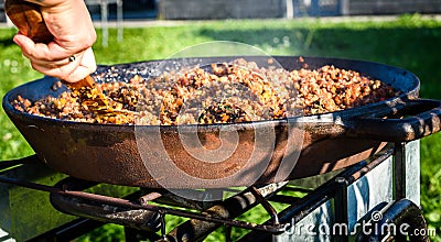 Cooking and making traditional Spanish Paella in iron cast pan. Stock Photo