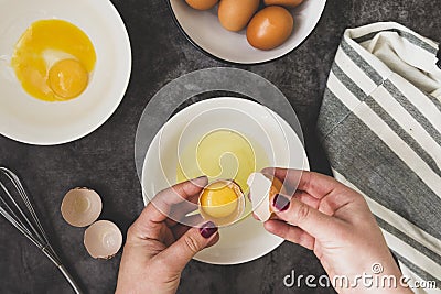 Cooking omlette. Woman& x27;s hands cookingomlette, breaking an fresh egg. Dark background. Food flat lay Stock Photo