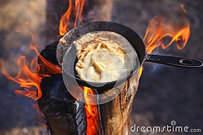 Cooking pancake in a pan on the fire of a Finnish candle Stock Photo