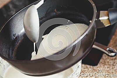 Liquid dough is poured onto frying pan Stock Photo