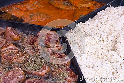 Pork knuckles, meat stew, rice in a big frying pan, street food, Stock Photo