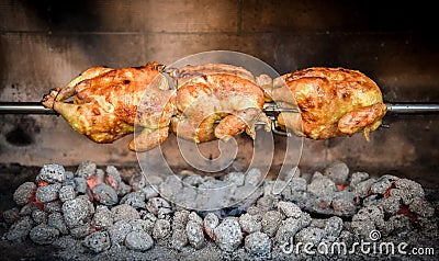 Cooking 3 rotisserie chicken on the grill with Charcoal and Briquettes Stock Photo