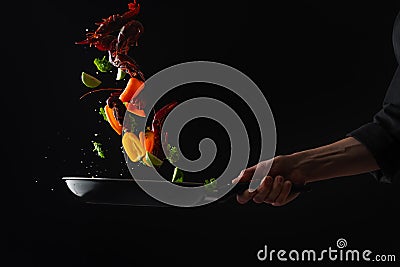 Cooking seafood, frying in a pan with vegetables, veggie healthy food, on a black background, menu and restaurant business Stock Photo