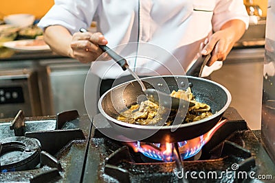 Chef Cooking Thai Food Cuisine in Skillet over Flames on Gas Stove Stock Photo