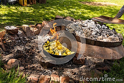 Cooking traditional dalmatian, croatian, bosnian dish called peka. Meat, potatoes and vegetables in pot and covered with hot Stock Photo