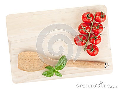 Cooking utensil and tomato with basil over cutting board Stock Photo