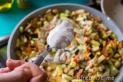 Cooking vegetarian meal. Putting too much salt in vegetables Stock Photo