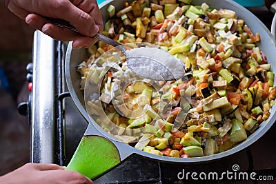 Cooking vegetarian meal. Putting too much salt in vegetables Stock Photo