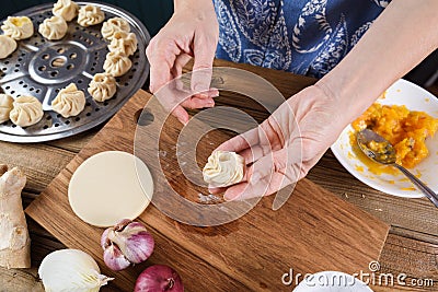 Cooking vegetarian meal. Woman hands making traditional Asian steamed dumplings with pumpkin, onion and ginger Stock Photo