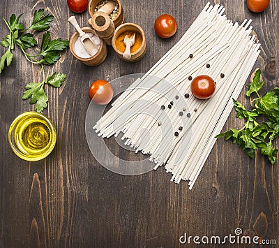 Cooking vegetarian noodles with cherry tomatoes, herbs and spices and oil on a wooden background, noodles lies in vintage pot sp Stock Photo