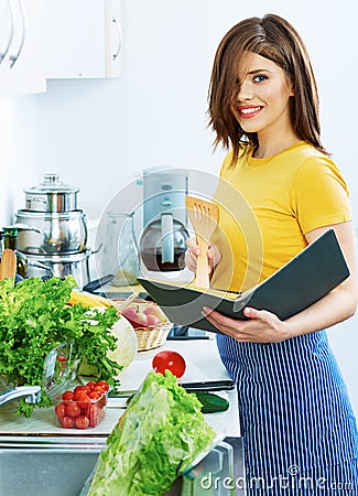 Cooking woman standing in kitchen, reed recipe from menu Stock Photo