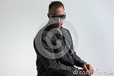 Cool bearded guy wearing grey denim jacket and sunglasses and posing Stock Photo