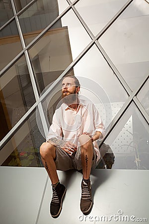 Cool bearded tattooed guy posing in front of office building Stock Photo