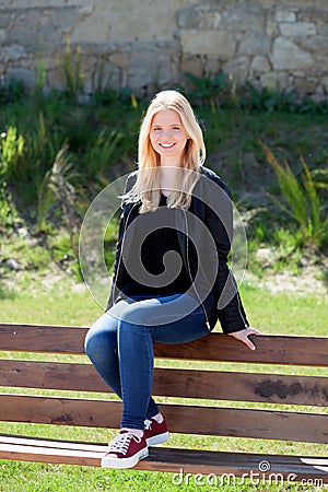 Cool blonde girl sitting on a wooden bench Stock Photo