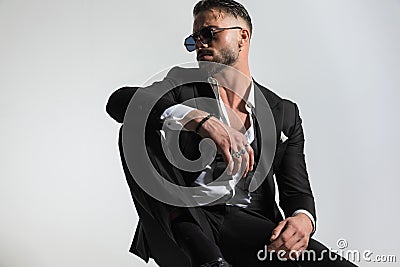 Cool elegant guy with undone bowtie and shirt holding knee up Stock Photo