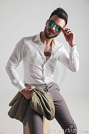 Cool fashion man sitting and putting on his sunglasses Stock Photo