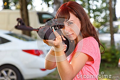 Cool female sniper aiming from telescopic rifle Stock Photo