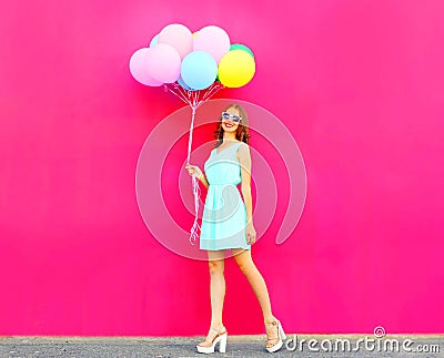 Cool girl with an air colorful balloons walking over a pink Stock Photo