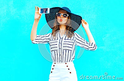 Cool girl is taking a picture on a smartphone wearing a straw hat Stock Photo