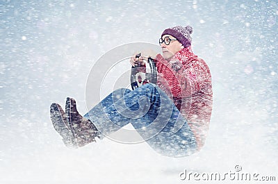 Cool man driver in round glasses, red sweater, and hat, with steering wheel. Winter, snow, blizzard Stock Photo