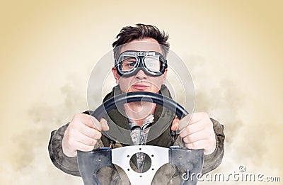 Cool man in stylish goggles with steering wheel, smoke around, yellow background. Front view. Car driver concept Stock Photo