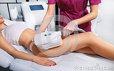 Young woman getting cryolipolyse treatment in cosmetic cabinet. Fat freezing technology on legs. Cool sculpting procedure Stock Photo