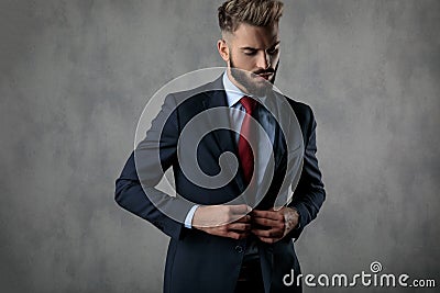 Cool young businessman buttoning his suit and looks down Stock Photo