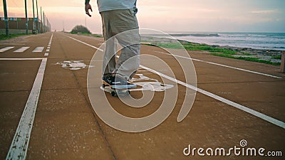 Cool skater riding road near sea coast back view. Unknown extremal man skating. Stock Photo