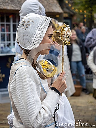 Teenage lady in traditional Danish costume holding up a venetian mask Editorial Stock Photo