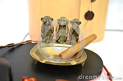 Copper ashtray with cigar and three monkeys Stock Photo