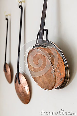 Copper pots and kitchen utinsils hanging on a white painted wall Stock Photo