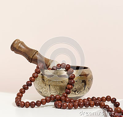 Copper singing bowl and wooden clapper on a white table. Musical instrument for meditation, relaxation, various medical practices Stock Photo