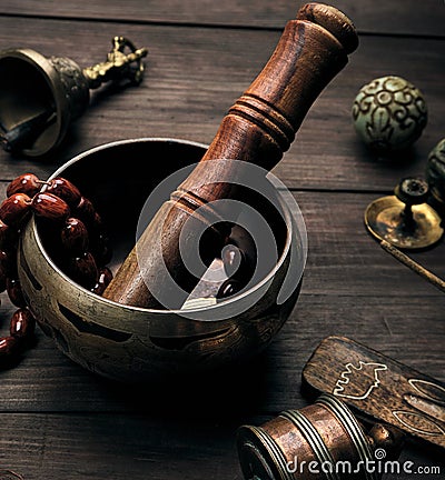 copper singing bowl and a wooden stick on a brown table Stock Photo