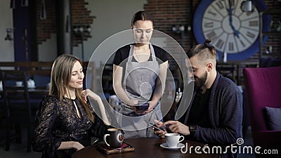 Coppie che pagano con il telefono la cena Giovani coppie che si siedono nel ristorante e maschio che paga la cena con il telefono stock footage Coppie che pagano con il telefono la cena Giovani coppie che si siedono nel ristorante e maschio che paga la cena con il telefono stock footage