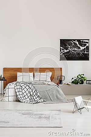 Copy space on white wall with black map in modern bedroom with king size bed with wooden headboard Stock Photo