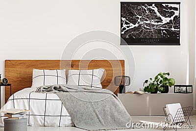 Copy space on white wall with black map in modern bedroom with king size bed with wooden headboard Stock Photo