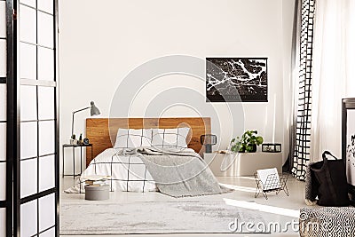 White wall with black map in modern bedroom with king size bed with wooden headboard Stock Photo