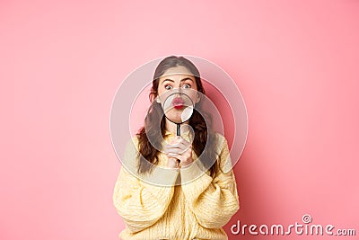 Coquettish silly woman showing her pucker lips, kissing face with magnifying glass near mouth, staring funny at camera Stock Photo