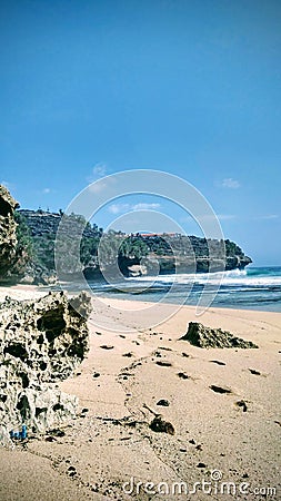 Coral cliff on a sandy beach in a sunny day with wavy sea Stock Photo