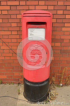 Corby, U.K., June 20, 2019 - traditional british red postbox near brick wall Editorial Stock Photo