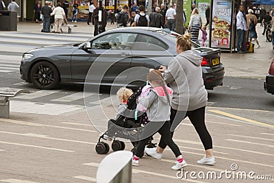 Corby, United Kingdom - august 28, 2018: Young mother walking in street with two childrens and pushchair. Active family outdoors. Editorial Stock Photo