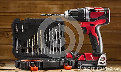 Cordless drill driver in red with rubberized handle in profile with drill bits set Stock Photo