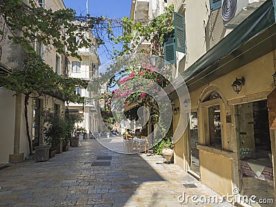 Corfu old town cobble stone street with cafe and flower garlands, summer sunny day, Corfu island, Ionian islands, Greece Stock Photo