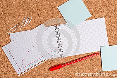 Corkboard desk with a open square paper spiral notebook and office appliances. Billboard table with different sizes and Stock Photo