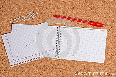 Corkboard desk with a open square paper spiral notebook and office appliances. Billboard table with different sizes and Stock Photo