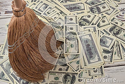 Corn broom sweeps pile of money. Stock Photo