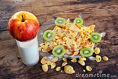 Corn flakes with apples and kiwi on plate with spoons against old wooden table Stock Photo