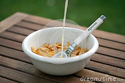 Corn flakes in white bowl spoon inside adding milk Stock Photo